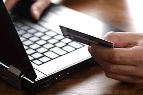 A person setting at a desktop reading a credit card